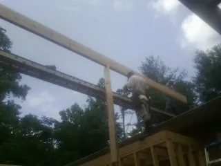 Carpenter setting a ridge beam over a new addition frame — Ice Dam Removal by Roofing Brothers in Girard