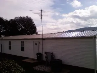 New metal roof on a single wide mobile home with a TV antenna in Girard