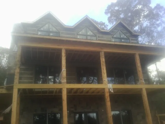 Dormers and porch framing on a large log home under construction — Roof Coating work by our crew in Girard