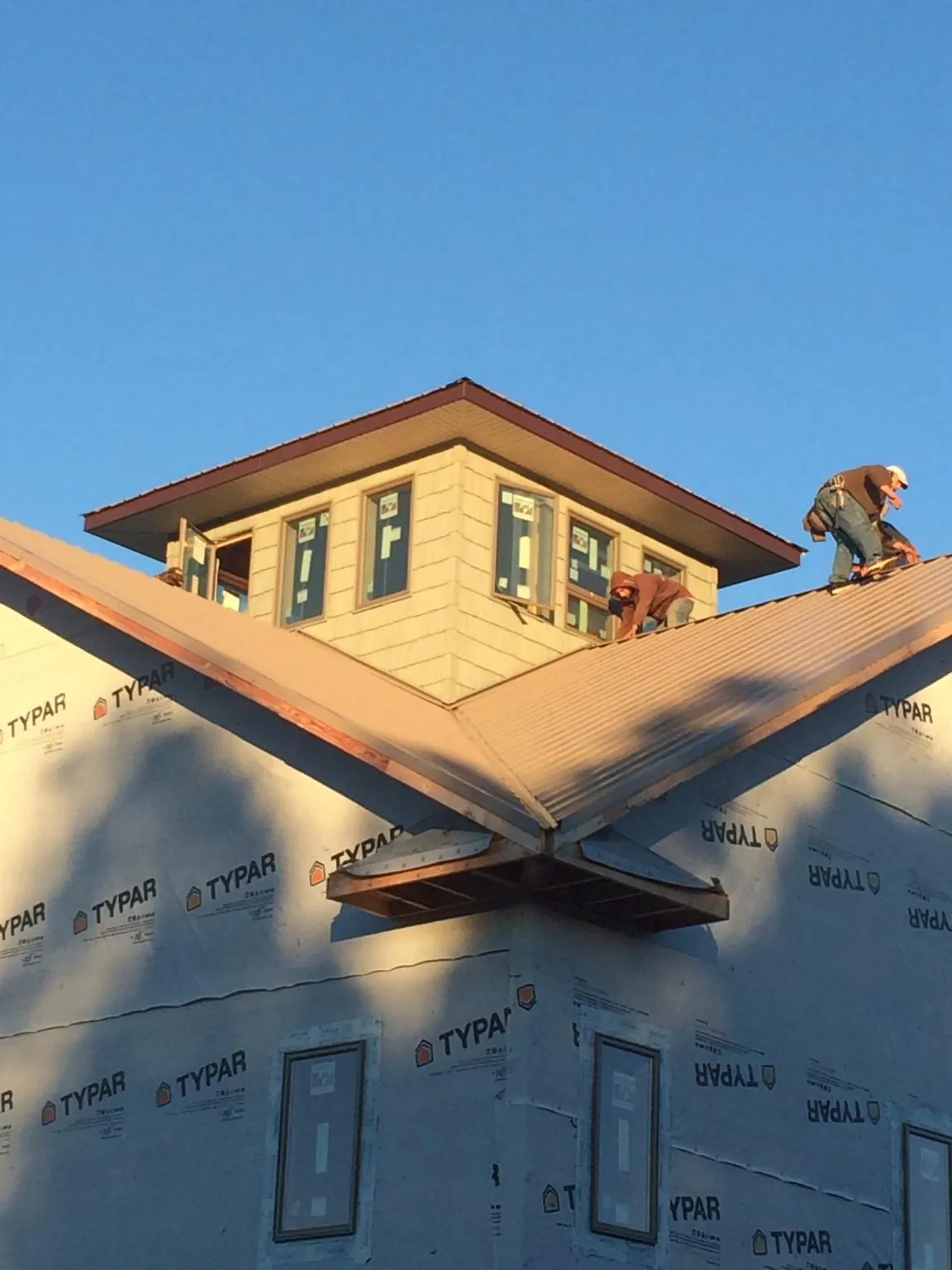 Roofers working around a rooftop cupola on a new metal roof at sunset — Roof Waterproofing in Girard by Roofing Brothers